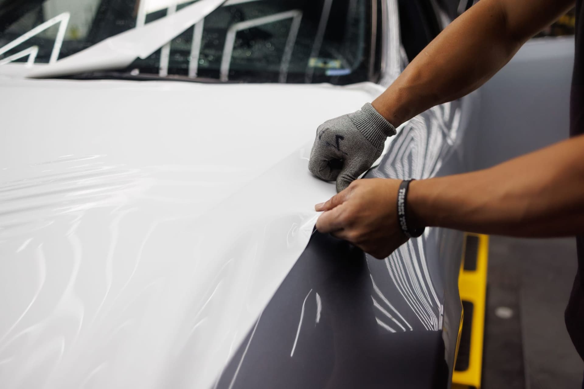 An installer smoothing vinyl film over a vehicle panel