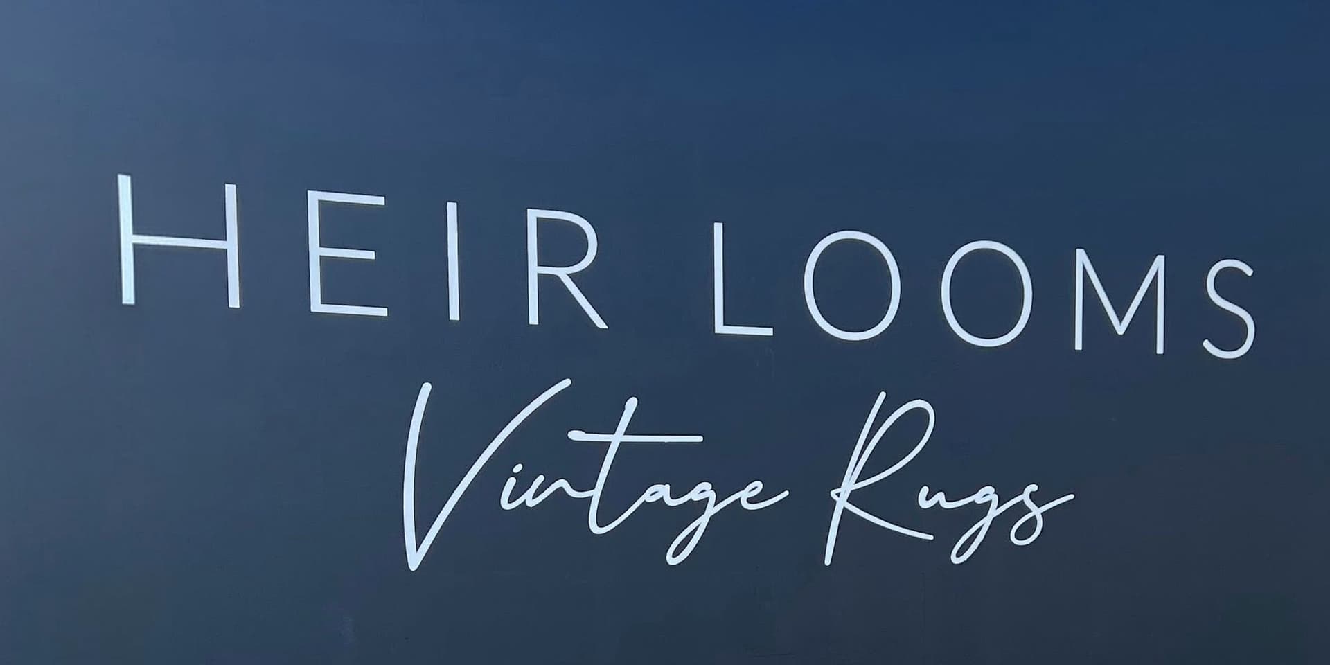 White serif and script lettering on a navy showroom wall