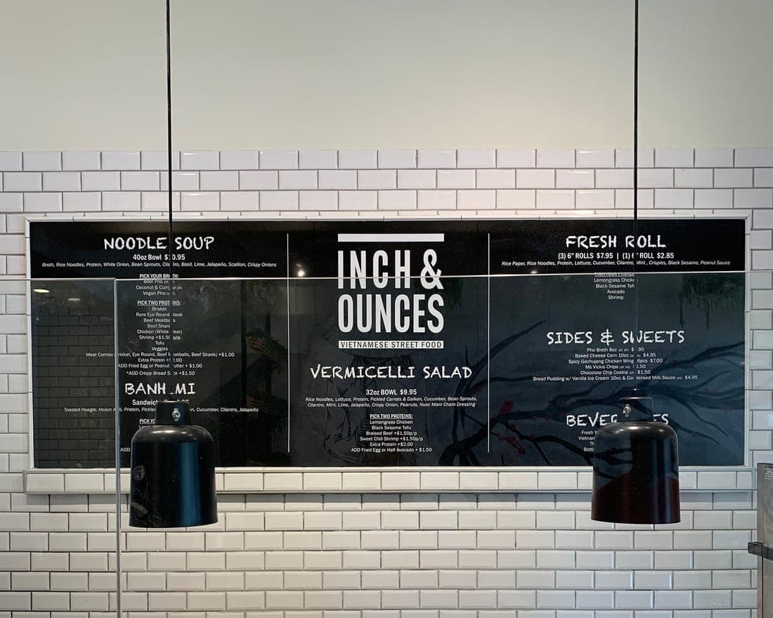 Menu boards mounted on a white tile wall behind a counter