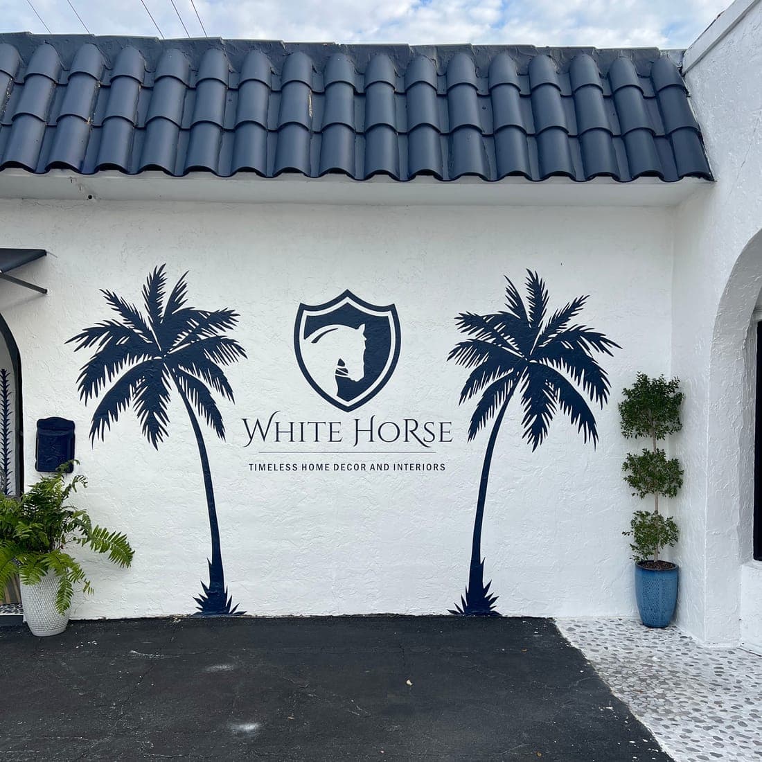 Palm tree and crest wall graphics on white stucco under a barrel-tile roof