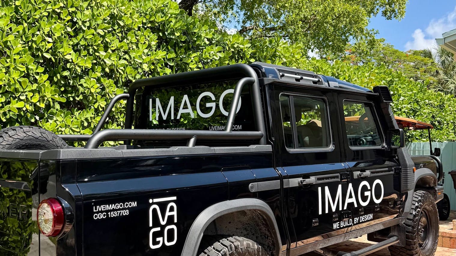 A black pickup with white cut-vinyl fleet graphics under South Florida trees