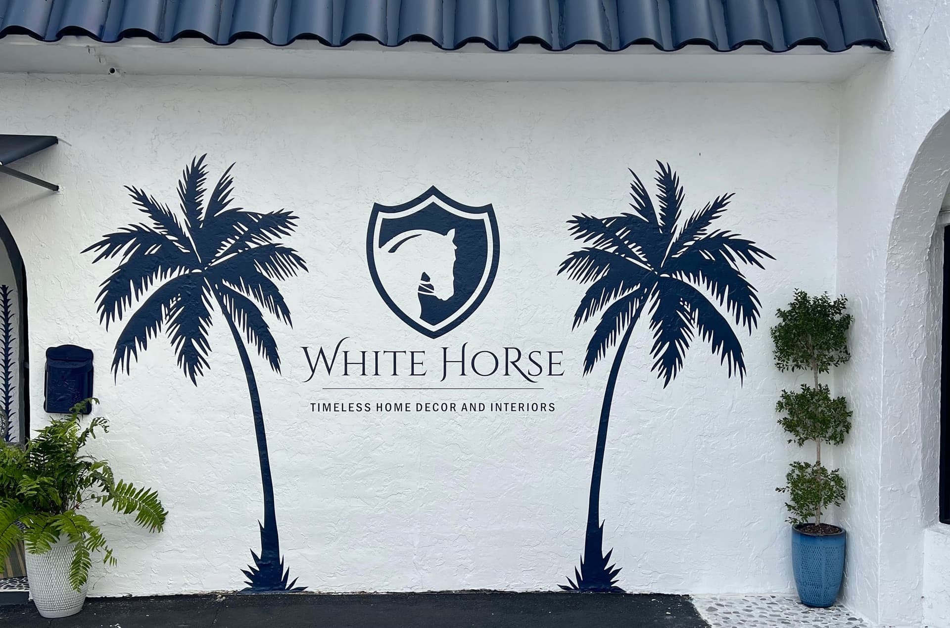 A palm mural and crest painted on a white stucco wall